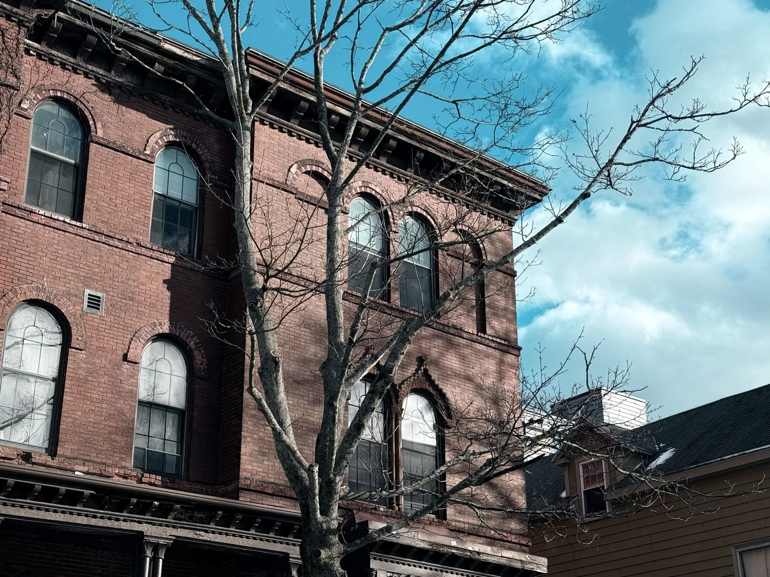 Brick row house with arched windows against a Maine spring sky